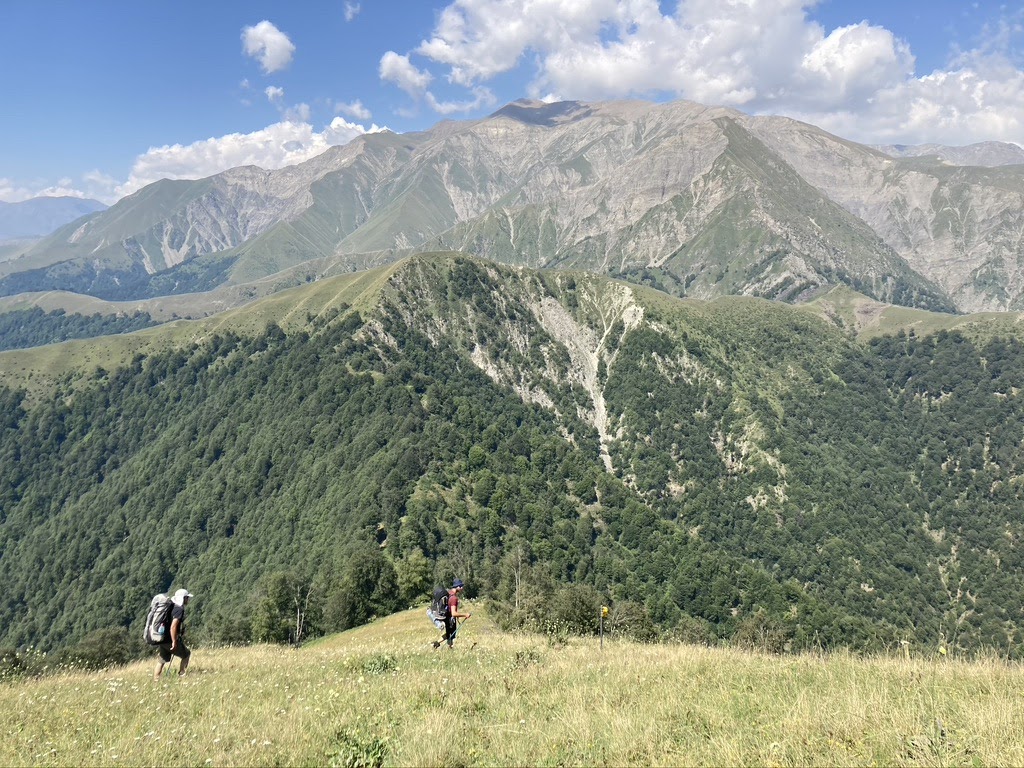 Two hikers on a ridge trail with Caucasus peaks behind, Azerbaijan