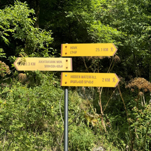 Trail signpost showing distances to Hovk, Gosh, and a hidden waterfall on the Armenia route