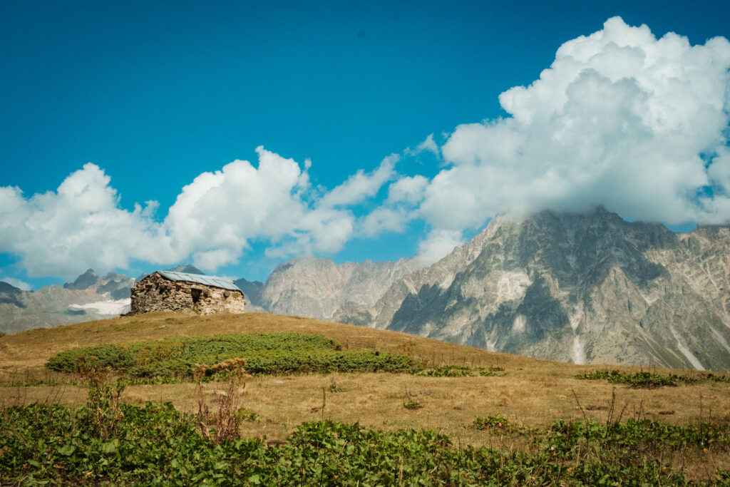 Stone Svan tower on a ridge with a rocky peak behind, Svaneti, Georgia