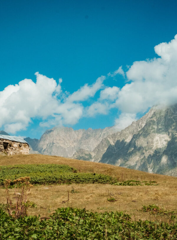 Stone Svan tower on a ridge with a rocky peak behind, Svaneti, Georgia