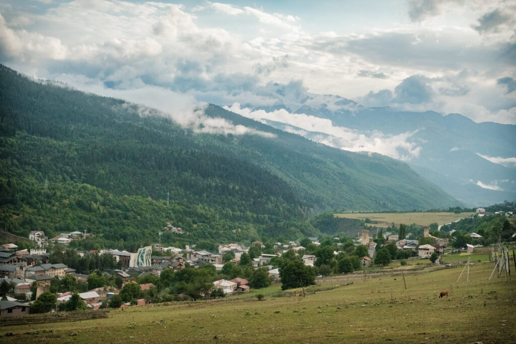 Svan tower village in a green valley beneath cloud-wrapped peaks, Svaneti, Georgia