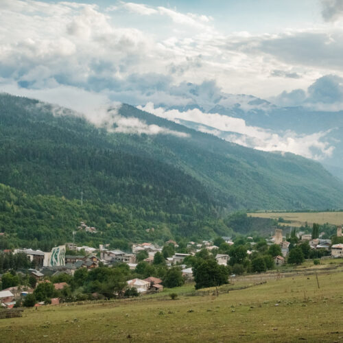 Svan tower village in a green valley beneath cloud-wrapped peaks, Svaneti, Georgia