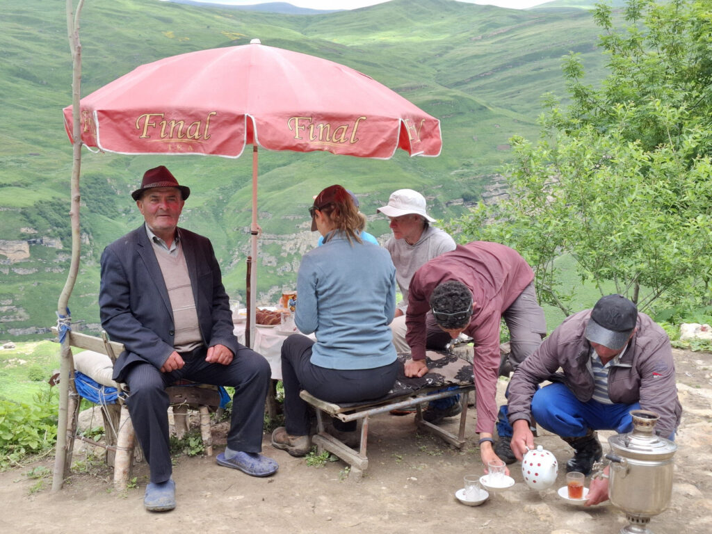 Hikers and local villagers gathered under a red canopy at a village stop in Azerbaijan