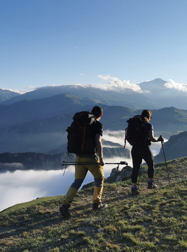 Two hikers walking a ridge above a sea of clouds filling the valley below, Azerbaijan